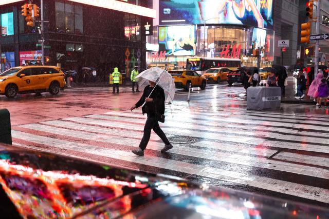 A person walks in the rain in Times Square in New York on August 27, 2026. (Photo by CHARLY TRIBALLEAU / AFP)