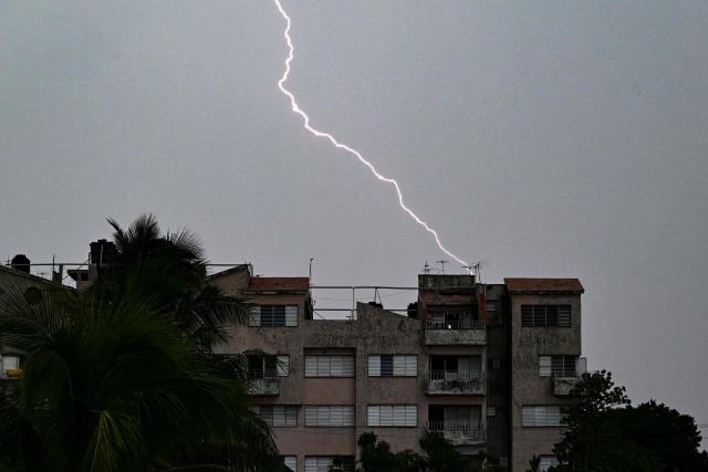Lightning strikes near an apartment building during a blackout in Havana on August 27, 2026. Four of eastern Cuba's five provinces suffered a blackout on August 27, the national power company said, blaming a transmission failure for the latest outage as the island reels from a US energy blockade. (Photo by YAMIL LAGE / AFP)