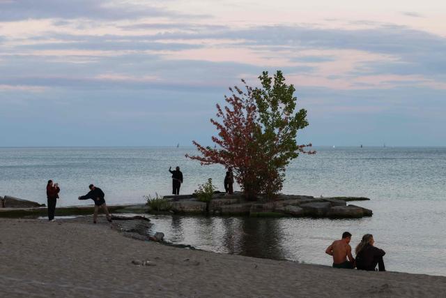People gather at dusk on the shore of Lake Ontario in Toronto, Ontario, on August 27, 2026. US President Donald Trump announced that he is renaming Lake Ontario -- a large body of water shared by the United States and Canada -- "Lake America." Trump signed an order in the White House in a move that comes amid a spiraling trade war between the world's largest economy and its northern neighbor. (Photo by Cole Burston / AFP)