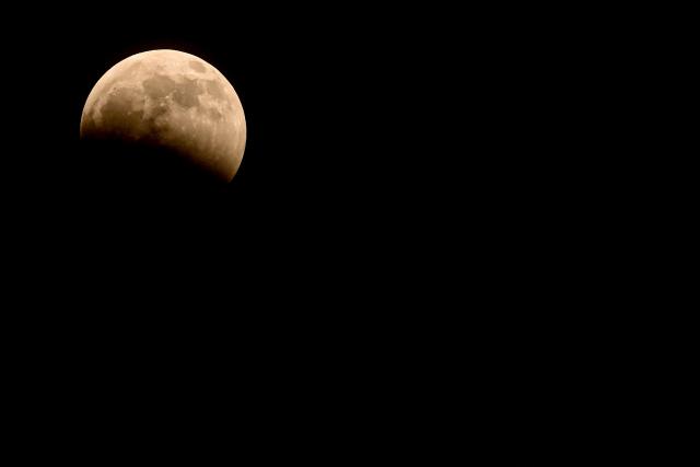 The moon enters the Earth's umbra during a partial lunar eclipse over Panama City on August 27, 2026. (Photo by MARTIN BERNETTI / AFP)