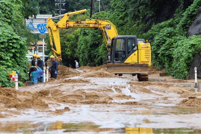 Workers remove mud and debris from a road after heavy rainfall in Takaoka, Toyama prefecture on August 28, 2026. (Photo by JIJI PRESS / AFP) / Japan OUT