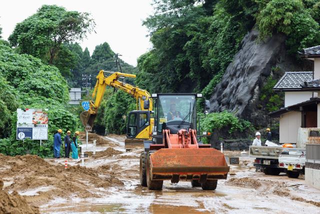 Workers remove mud and debris from a road after heavy rainfall in Takaoka, Toyama prefecture on August 28, 2026. (Photo by JIJI PRESS / AFP) / Japan OUT