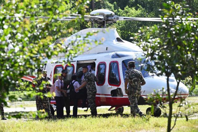 School children board a helicopter on a transit flight back to their family at Trishuli camp after being stranded by flash floods in Nepal's Nuwakot district on August 28, 2026. China and Nepal warned of fresh flooding risks, complicating rescuers' search for more than 1,400 people missing after a deadly deluge and landslides swept away entire villages along their remote Himalayan border. (Photo by Arun SANKAR / AFP)