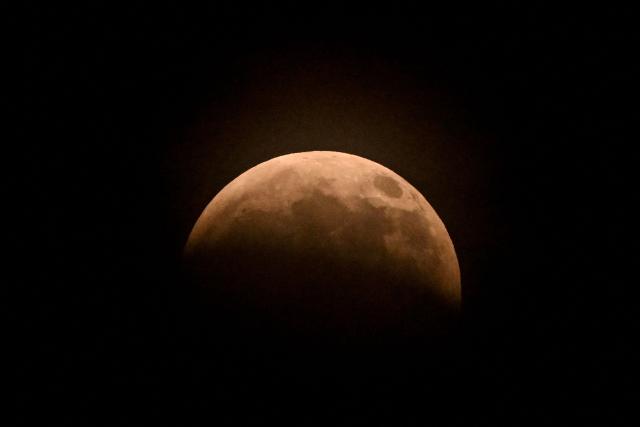 The moon turns red during a partial lunar eclipse over Mexico City on August 27, 2026. (Photo by Yuri CORTEZ / AFP)