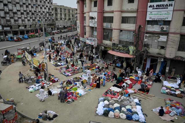 People shop for clothes at a roadside flea market in Karachi on August 28, 2026. (Photo by Rizwan TABASSUM / AFP)