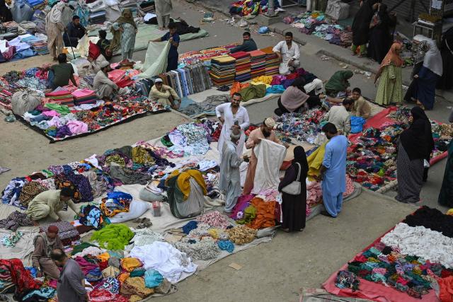 People shop for clothes at a roadside flea market in Karachi on August 28, 2026. (Photo by Rizwan TABASSUM / AFP)
