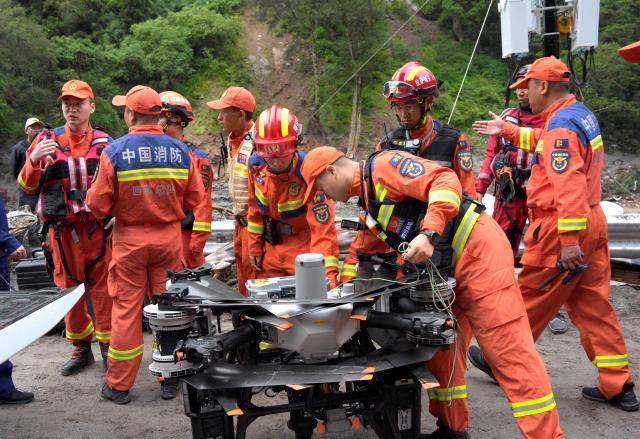 Fire and rescue personnel prepare a drone before carrying out rescue operations on a section of a road leading to Gyirong Port which was damaged after a mudslide two days earlier, in Gyirong County, in China’s western Tibet region on August 28, 2026. (Photo by CNS / AFP) / China OUT