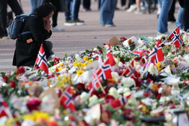 A woman pays tribute in front of flags of Norway and flowers to King Harald V of Norway who passed away, at the Royal Palace square in Oslo on August 28, 2026. King Harald V of Norway, who died on August 28, 2026 aged 89, remained a unifying figure in his country until the very end, a pillar of stability amid a string of family scandals that tarnished the final years of his reign. (Photo by Odd ANDERSEN / AFP)