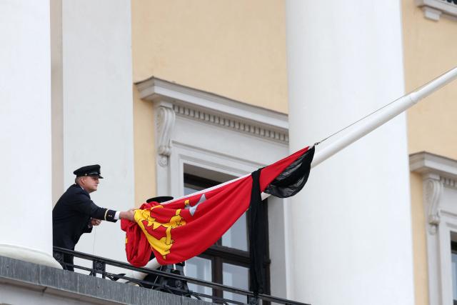 The royal flag with a black ribbon is raised to half-mast by members of the Royal Guards from the balcony of the royal palace after King Harald V of Norway passed away in Oslo, Norway on August 28, 2026. King Harald V of Norway, who died on August 28, 2026 aged 89, remained a unifying figure in his country until the very end, a pillar of stability amid a string of family scandals that tarnished the final years of his reign. (Photo by Odd ANDERSEN / AFP)