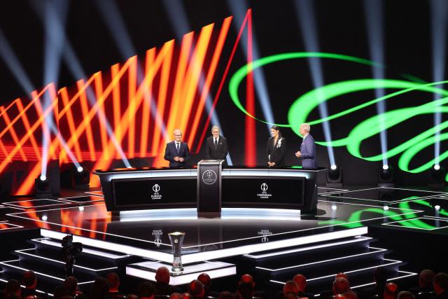 UEFA Deputy General Secretary Giorgio Marchetti (L), Turkish former footballer Metin Tekin (2nd L) and hosts Becky Ives (2nd R) and Matt Smith (R) attend the draw ceremony for the league phase of the 2026-2027 UEFA Conference League football tournament at the Grimaldi Forum in the Principality of Monaco on August 28, 2026. (Photo by Valery HACHE / AFP)