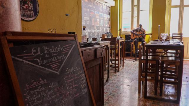 A musician performs beside empty tables at El Balcon de los Hermanos restaurant in Havana on August 22, 2026. Opening a restaurant in today's Cuba defies all logic. Amid power outages, shortages of supplies and a sharp decline in tourism, some Cubans keep their businesses open while others even take the risk of launching new establishments. (Photo by ADALBERTO ROQUE / AFP)