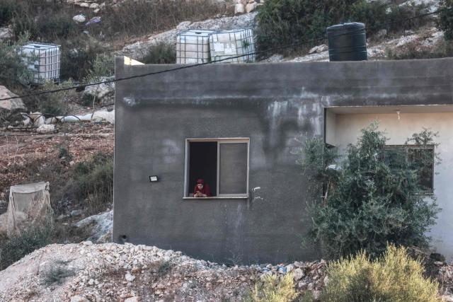 A Palestinian woman looks at her mobile phone as Israeli soldiers (unseen) gather nearby following a drone strike that killed three Palestinians, on the western outskirts of the northern city of Jenin, in the Israeli-occupied West bank on August 28, 2026. (Photo by Jaafar ASHTIYEH / AFP)