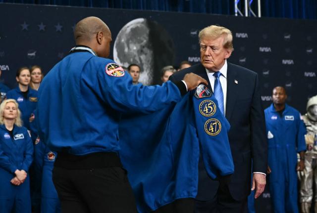 NASA astronaut and pilot Victor Glover hands US President Donald Trump a jacket after presenting the Artemis II crew members with the Congressional Space Medal of Honor at NASA Lyndon B. Johnson Space Center in Houston, Texas, on August 28, 2026. The Artemis II astronauts crew are honored with the Congressional Space Medal of Honor for their historic mission around the Moon. (Photo by Kent NISHIMURA / AFP)