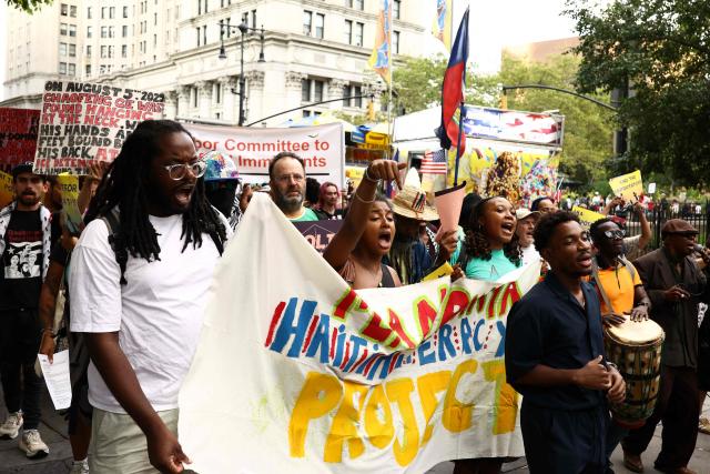 People hold signs during a protest against the termination of Temporary Protected Status (TPS) for the Haitian community and to end mass deportations, at Foley Square in New York City on August 28, 2026. The Supreme Court said in late June 2026 that the Trump administration is allowed to end Temporary Protected Status (TPS) for Haitians and some 6,000 Syrians without judicial review, although the impact of the decision could apply to migrants from many other backgrounds. An estimated 350,000 Haitians live in the United States under the program, with many working in healthcare and construction. (Photo by CHARLY TRIBALLEAU / AFP)