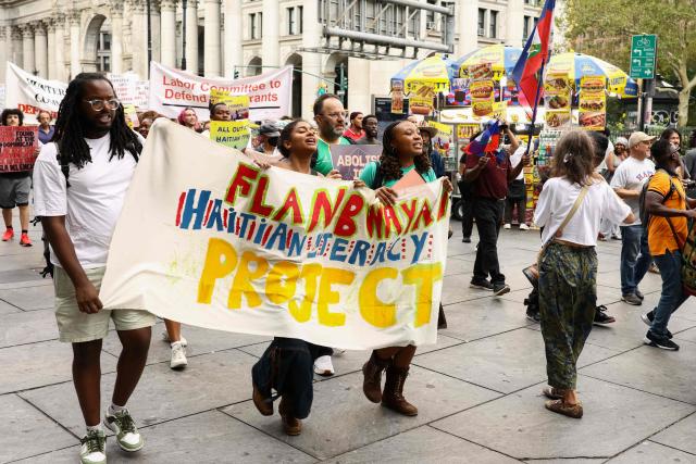 People hold signs during a protest against the termination of Temporary Protected Status (TPS) for the Haitian community and to end mass deportations, at Foley Square in New York City on August 28, 2026. The Supreme Court said in late June 2026 that the Trump administration is allowed to end Temporary Protected Status (TPS) for Haitians and some 6,000 Syrians without judicial review, although the impact of the decision could apply to migrants from many other backgrounds. An estimated 350,000 Haitians live in the United States under the program, with many working in healthcare and construction. (Photo by CHARLY TRIBALLEAU / AFP)