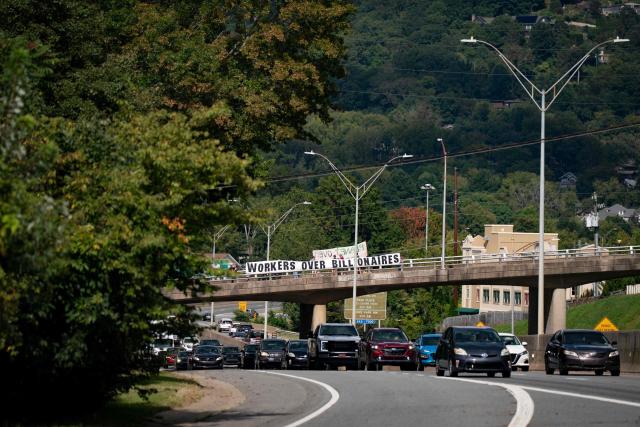 People hold a banner reading "workers over billionaires" on a freeway overpass as they protest ahead of the G20 Finance ministers and central bank governors meeting on August 28, 2026, in Asheville, North Carolina. Asheville is hosting the G20 meetings from August 29 to September 1. (Photo by Allison Joyce / AFP)
