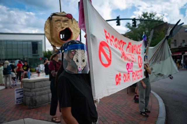 People hold a banner reading "fascist finance ministers out of our forests" as they protest ahead of the G20 Finance ministers and central bank governors meeting on August 28, 2026, in Asheville, North Carolina. Asheville is hosting the G20 meetings from August 29 to September 1. (Photo by Allison Joyce / AFP)