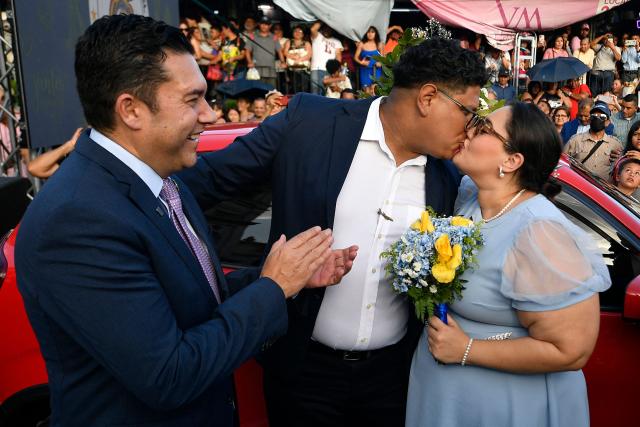 Tegucigalpa's Mayor Juan Diego Zelaya (L) claps next to a newly-wed couple who won a car during a mass wedding as part of the Family Month celebration in front of the Church of Santa Maria de los Dolores in Tegucigalpa on August 28, 2026. (Photo by Orlando SIERRA / AFP)