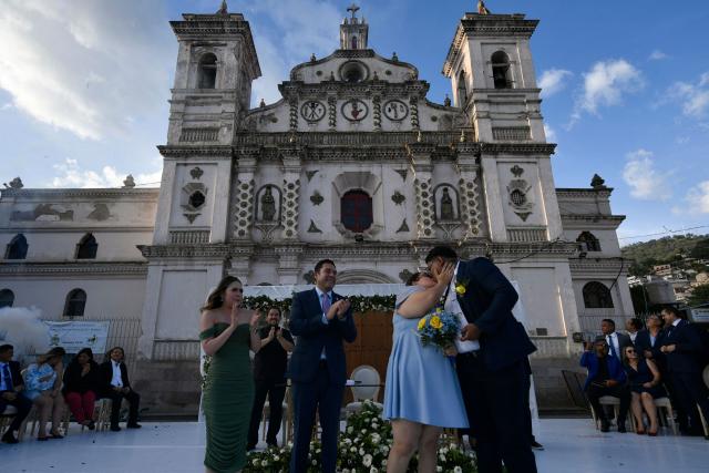 Tegucigalpa's Mayor Juan Diego Zelaya (2nd L) and his wife Paola Rubi (L) clap next to a newly-wed couple during a mass wedding as part of the Family Month celebration in front of the Church of Santa Maria de los Dolores in Tegucigalpa on August 28, 2026. (Photo by Orlando SIERRA / AFP)
