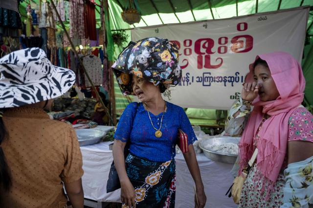 People walk along market stalls as they visit the annual Taungbyone Spirit Festival in Madaya township, Mandalay region on August 26, 2026. As monsoon rains pound the heartlands of war-fractured Myanmar, "spirit consorts" gather to renew their vows with a pantheon of gods hailed for their powers to protect and destroy. (Photo by SAI AUNG MAIN / AFP) / TO GO WITH AFP STORY: Myanmar-religion-festival-conflict, FOCUS