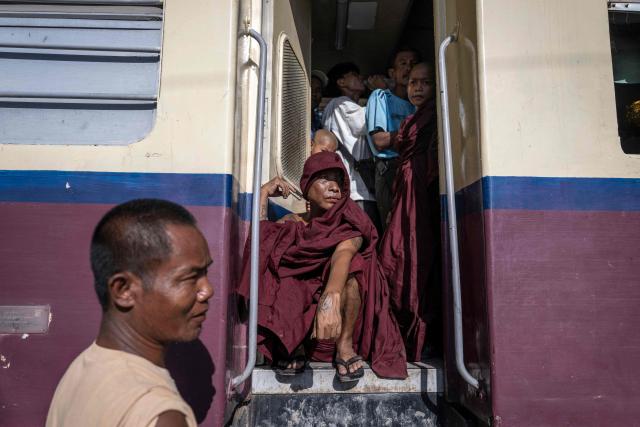 Devotees stand near by open doorway inside a crowded commuter train travelling between Mandalay and Taungbyone for the annual Taungbyone Spirit Festival in Madaya township, Mandalay region on August 26, 2026. As monsoon rains pound the heartlands of war-fractured Myanmar, "spirit consorts" gather to renew their vows with a pantheon of gods hailed for their powers to protect and destroy. (Photo by SAI AUNG MAIN / AFP) / TO GO WITH AFP STORY: Myanmar-religion-festival-conflict, FOCUS
