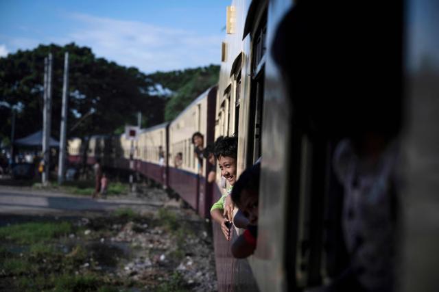 People look outside of a crowded commuter train travelling between Mandalay and Taungbyone for the annual Taungbyone Spirit Festival in Madaya township, Mandalay region on August 26, 2026. As monsoon rains pound the heartlands of war-fractured Myanmar, "spirit consorts" gather to renew their vows with a pantheon of gods hailed for their powers to protect and destroy. (Photo by SAI AUNG MAIN / AFP) / TO GO WITH AFP STORY: Myanmar-religion-festival-conflict, FOCUS