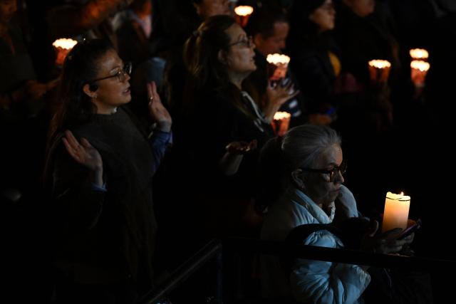 People hold candles during a vigil in honor of the earthquake victims at Bolivar square in Bogota, on August 28, 2026. (Photo by Raul ARBOLEDA / AFP)