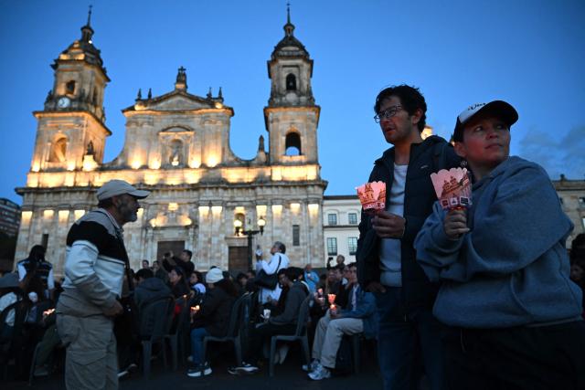 People hold candles during a vigil in honor of the earthquake victims at Bolivar square in Bogota, on August 28, 2026. (Photo by Raul ARBOLEDA / AFP)