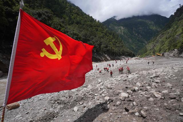 A Communist Party flag flies as paramilitary police conduct search and rescue operations near Gyirong Port, following a mudslide two days earlier, in Gyirong County, in China’s western Tibet region on August 28, 2026. (Photo by CNS / AFP) / China OUT