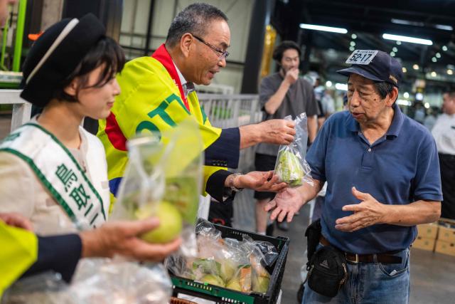 Representatives of agricultural cooperative JA Zen-Noh hand out samples of Tottori-grown Nijisseiki, or "20th Century" pears, to buyers ahead of the season's first auction at Ota Market in Tokyo on August 29, 2026. The auction took place two days after a record 600,000 yen (USD 3,748) was paid for a 10-kilogram box of the pear variety at the season's opening auction in Osaka. First introduced in 1904 and now a signature product of Tottori Prefecture, the variety is among Japan's best-known pears. (Photo by Andrew CABALLERO-REYNOLDS / AFP)