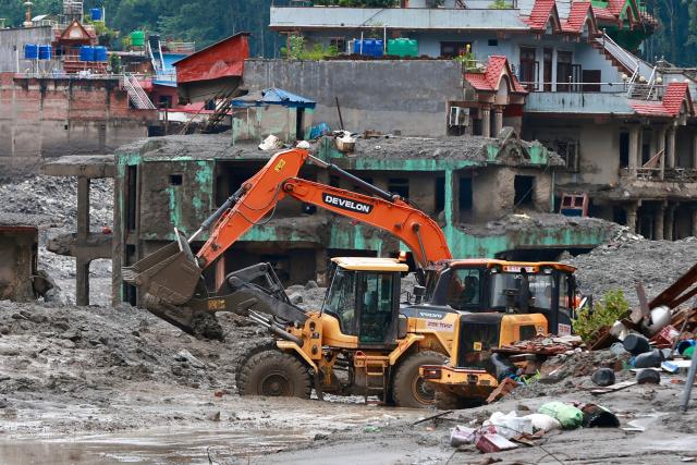 Workers use excavators to clear the mud at the Dhunge Bazaar in Nepal's Nuwakot district on August 29, 2026 after flash floods and landslides hit the Nepal-Tibet border. Rescuers in Nepal and China were still battling August 29 to locate thousands of people missing days after a deadly, tsunami-like wall of water and debris swept through the Himalayan region, engulfing villages. The number of missing soared past 2,400 on August 28 as emergency teams said they had recovered 623 bodies -- with some of the dead possibly swept downstream as far away as India. (Photo by PRABIN RANABHAT / AFP)