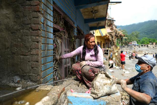 A woman tries to salvage belongings from her house heavily covered in mud in the aftermath of flash floods at Devighat in Nepal's Nuwakot district on August 29, 2026. Rescuers in Nepal and China were still battling on August 29 to locate thousands of people missing days after a deadly, tsunami-like wall of water and debris swept through the Himalayan region, engulfing villages. Nearly 3,000 people were still missing on August 29 and 633 confirmed dead after flash floods and landslides hit the Nepal-Tibet border. (Photo by Manan VATSYAYANA / AFP)