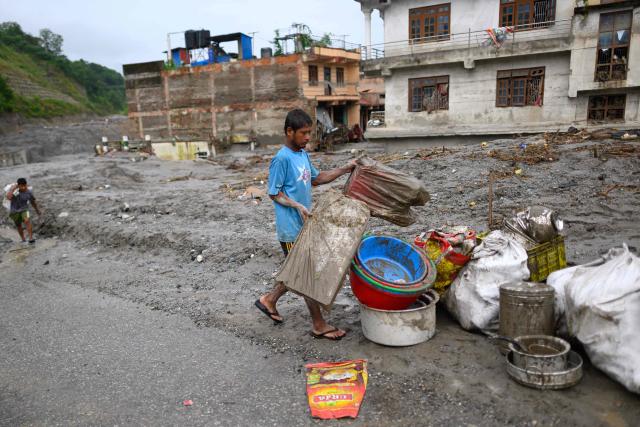 A man salvages his belongings from his house in the aftermath of flash floods at Devighat in Nepal's Nuwakot district on August 29, 2026. Rescuers in Nepal and China were still battling on August 29 to locate thousands of people missing days after a deadly, tsunami-like wall of water and debris swept through the Himalayan region, engulfing villages. Nearly 3,000 people were still missing on August 29 and 633 confirmed dead after flash floods and landslides hit the Nepal-Tibet border. (Photo by Manan VATSYAYANA / AFP)