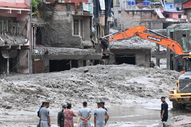 An excavator (top) helps people to collect some of their belongings from their house in the aftermath of flash floods at Trishuli, in Nepal's Nuwakot district on August 29, 2026. Nearly 3,000 people were still missing on August 29 and 633 confirmed dead after flash floods and landslides hit the Nepal-Tibet border. (Photo by Arun SANKAR / AFP)