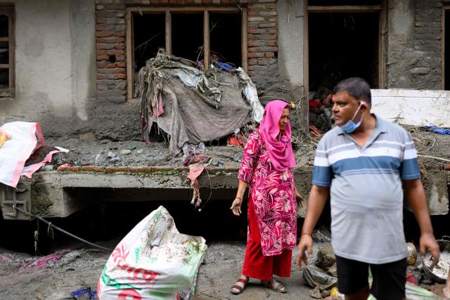 A family salvages their belongings from a house heavily covered in mud following flash floods at Devighat in Nepal’s Nuwakot district on August 29, 2026. Rescuers in Nepal and China were still battling on August 29 to locate thousands of people missing days after a deadly, tsunami-like wall of water and debris swept through the Himalayan region, engulfing villages. Nearly 3,000 people were still missing on August 29 and 633 confirmed dead after flash floods and landslides hit the Nepal-Tibet border. (Photo by Manan VATSYAYANA / AFP)