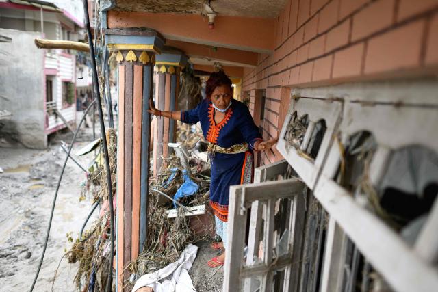 A woman salvages her belongings from her house heavily covered in mud following flash floods at Devighat in Nepal's Nuwakot district on August 29, 2026. Nearly 3,000 people were still missing on August 29 and 633 confirmed dead after flash floods and landslides hit the Nepal-Tibet border. (Photo by Manan VATSYAYANA / AFP)