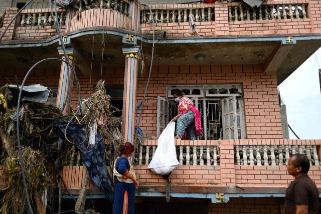 A woman salvages her belongings from her house heavily covered in mud in the aftermath of flash floods at Devighat in Nepal's Nuwakot district on August 29, 2026. Nearly 3,000 people were still missing on August 29 and 633 confirmed dead after flash floods and landslides hit the Nepal-Tibet border. (Photo by Manan VATSYAYANA / AFP)