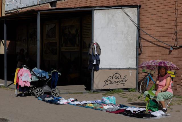 A street vendor sells her wares under a umbrella in Berehove on August 28, 2026, amid the Russian invasion of Ukraine. (Photo by Tetiana DZHAFAROVA / AFP)