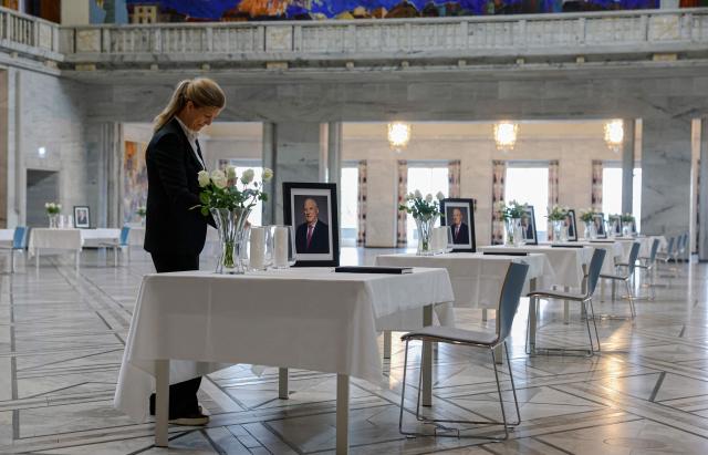 A staff member sets up tables displaying portraits of the late King inside Oslo City Hall in Oslo on August 29, 2026, for members of the public wishing to sign condolence books following his death. King Harald V of Norway, who died on August 28, 2026 aged 89, remained a unifying figure in his country until the very end, a pillar of stability amid a string of family scandals that tarnished the final years of his reign. (Photo by Odd ANDERSEN / AFP)