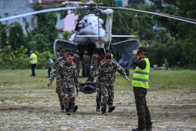 Army personnel carry an injured man during a rescue operation in the aftermath of flash floods, at Trishuli camp in Nuwakot district on August 29, 2026. Nearly 3,000 people were still missing on August 29 and 633 confirmed dead after flash floods and landslides hit the Nepal-Tibet border. (Photo by Arun SANKAR / AFP)