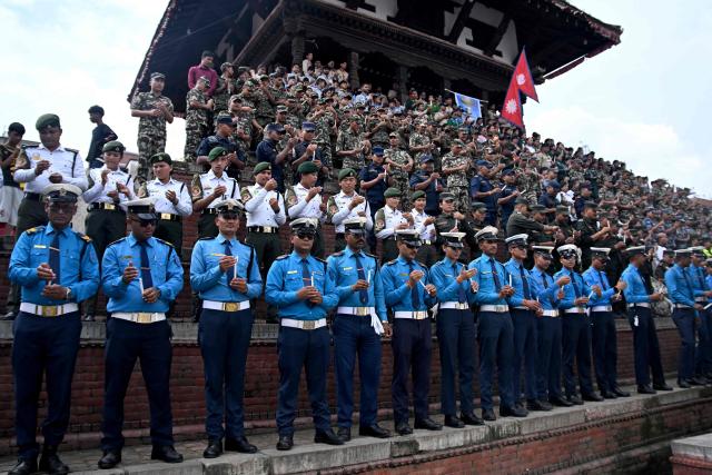 Security personnel offer prayers for flood victims during a candlelight vigil in Kathmandu on August 29, 2026. Rescuers in Nepal and China were battling on August 29 to locate thousands of people missing days after a deadly, tsunami-like wall of water and debris swept through the Himalayan region, engulfing entire villages. The latest figures from both countries put the number of missing close to 3,000, with 633 bodies recovered. (Photo by Prakash MATHEMA / AFP)