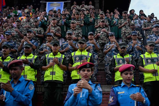 Security personnel offer prayers for flood victims during a candlelight vigil in Kathmandu on August 29, 2026. Rescuers in Nepal and China were battling on August 29 to locate thousands of people missing days after a deadly, tsunami-like wall of water and debris swept through the Himalayan region, engulfing entire villages. The latest figures from both countries put the number of missing close to 3,000, with 633 bodies recovered. (Photo by Prakash MATHEMA / AFP)
