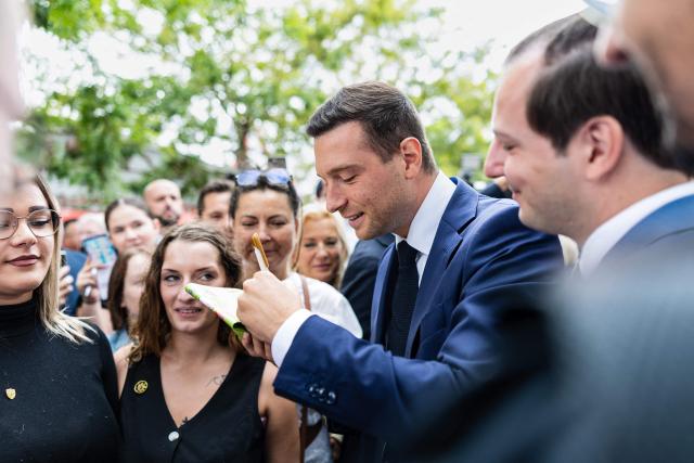 President of French far-right party Rassemblement National (RN) Jordan Bardella (Centre R) sign a copy of his book for members of the crowd during a visit to the agricultural fair in Châlons-en-Champagne, northeastern France on August 29, 2026. (Photo by Sameer Al-DOUMY / AFP)