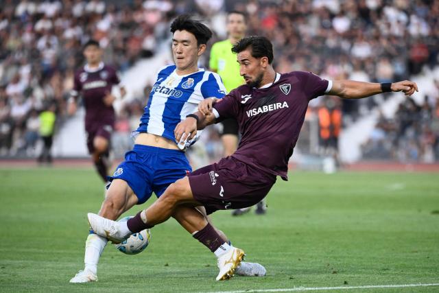 FC Porto's South Korean midfielder #16 Hwang In-beom (L) vies for the ball with Academico de Viseu's Portuguese midfielder #06 Andre Ceitil during the Portuguese League football match between Academico de Viseu F.C. and FC Porto at Estadio Municipal de Fontelo in Viseu on August 29, 2026. (Photo by Miguel RIOPA / AFP)
