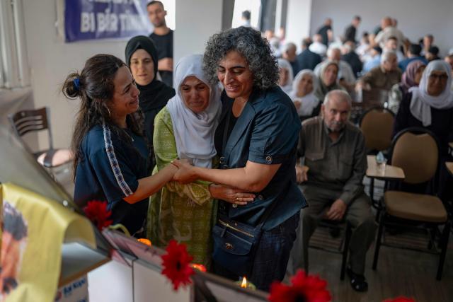 Former HDP MP Sebahat Tuncel (R) looks at photos with a relative during funeral commemorations of PKK guerrillas who had died as Kurdish families gathered to honor relatives killed in the conflict, in the Kucukcekmece district of Istanbul, on August 29, 2026. With the Turkish Parliament's adoption in mid-August of the Law on the Reintegration of Kurdish Fighters into Civilian Life, following twenty months of peace talks, the lists of "martyrs" are being gradually published by the authorities. (Photo by Yasin AKGUL / AFP)
