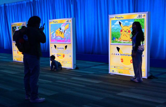 Attendees pose beside large Pokemon cards at the 2026 Pokemon World Championships and Pokemon XP at the Moscone Center in San Francisco, California on August 29, 2026. More than 50,000 fans are expected to be in attendance for the 3-day event from August 28-30 as the Pokemon World Championships return to San Francisco for the first time in a decade and for Pokemon XP, the first fan convention of its kind. The Pokemon franchise has an estimated global revenue of over $147 billion since launching in 1996, making it the world's most valuable media franchise. (Photo by Frederic J. BROWN / AFP)