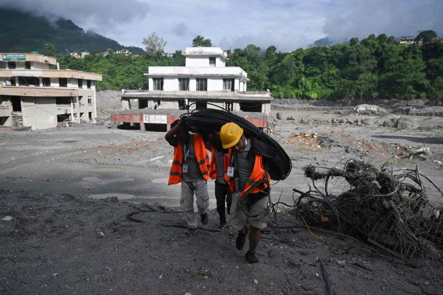Rescue workers carry cabling at the scene in Trishuli Center in Nepal's Nuwakot district on August 30, 2026, after catastrophic flooding on the Nepal-Tibet border. The number of people missing in the catastrophic flood that sliced through the border area between Nepal and Tibet neared 3,000 on August 30, as rescuers scoured deep, leg-sucking mud for survivors. (Photo by Arun SANKAR / AFP)
