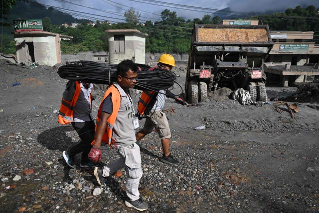 Rescue workers carry cabling at Trishuli Center in Nepal's Nuwakot district on August 30, 2026, after catastrophic flooding on the Nepal-Tibet border. The number of people missing in the catastrophic flood that sliced through the border area between Nepal and Tibet neared 3,000 on August 30, as rescuers scoured deep, leg-sucking mud for survivors. (Photo by Arun SANKAR / AFP)