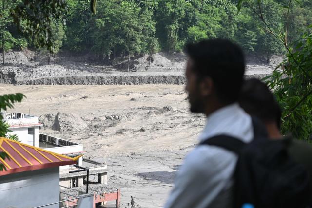 People look at the mud-inundated Trishuli river at Trishuli Center in Nepal's Nuwakot district on August 30, 2026, after catastrophic flooding on the Nepal-Tibet border. The number of people missing in the catastrophic flood that sliced through the border area between Nepal and Tibet neared 3,000 on August 30, as rescuers scoured deep, leg-sucking mud for survivors. (Photo by Arun SANKAR / AFP)