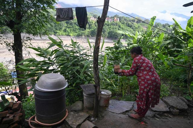 A resident tends to chores beside the mud-inundated Trishuli river at Trishuli Center in Nepal's Nuwakot district on August 30, 2026, after catastrophic flooding on the Nepal-Tibet border. The number of people missing in the catastrophic flood that sliced through the border area between Nepal and Tibet neared 3,000 on August 30, as rescuers scoured deep, leg-sucking mud for survivors. (Photo by Arun SANKAR / AFP)